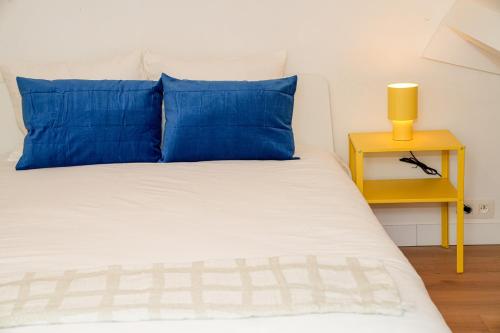 a bed with blue pillows and a yellow night stand at Chic & Modern 1BR & 1LR Apt, 12 Min Walk to Rabot in Ghent