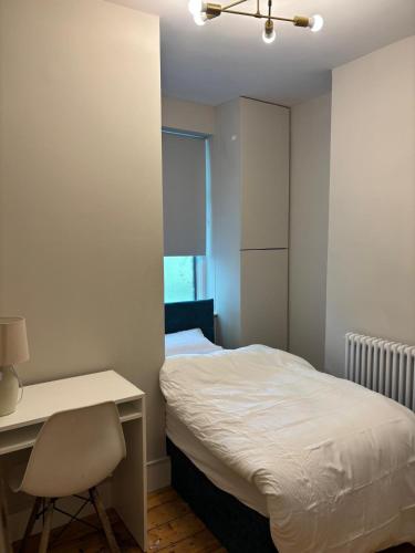 a bedroom with a bed and a desk and a chair at Stylish Four-Bed Haven Near Greenwich in Plumstead