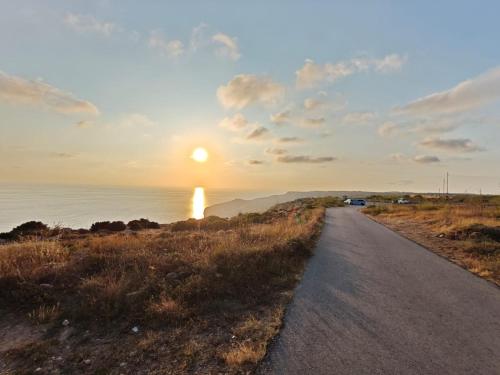 a road leading to the ocean with a sunset at Tan-Nanniet Penthouse in Dingli in Dingli