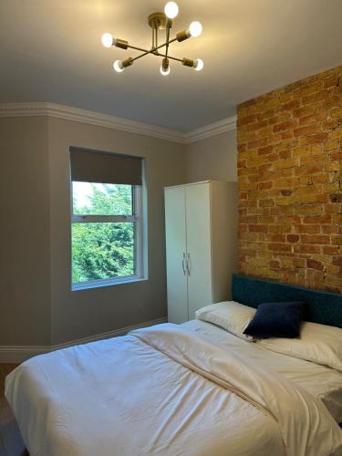 a bedroom with a large bed with a brick wall at Stylish Four-Bed Haven Near Greenwich in Plumstead