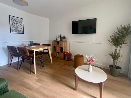 un salon avec une table et une télévision au mur dans l'établissement Cocoon Albatros, Golf view, pool, pine trees and ocean, à Moliets-et-Maa