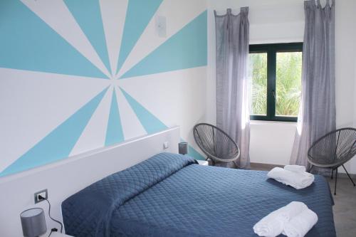 a bedroom with a blue bed and two chairs at Villa Anita Apartments in Capo dʼOrlando