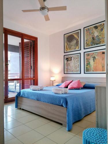 a bedroom with a bed with blue sheets and pink pillows at Sulla spiaggia di Letojanni in Letojanni