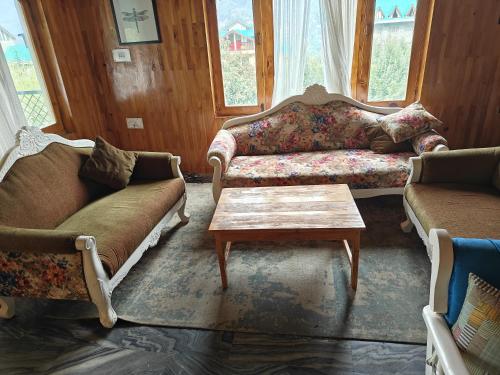 a living room with two couches and a coffee table at Apple Garden Cottage in Manāli