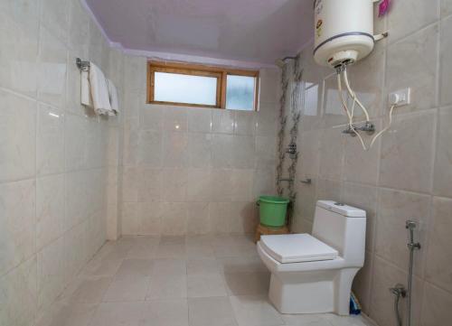a bathroom with a toilet and a window at Apple Garden Cottage in Manāli