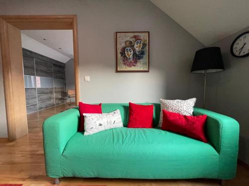 a green couch with red pillows in a living room at Smart Stay Apartment Samobor in Samobor
