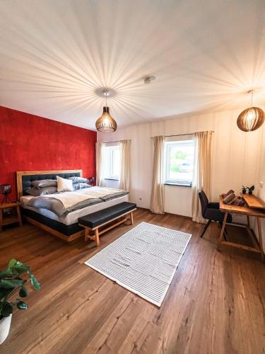 une chambre avec un lit et un mur rouge dans l'établissement Deluxe-Wohnung in Wasserburg Bahnhof - 94m2 - Smart TV - Terrasse - NEU, à Wasserburg am Inn