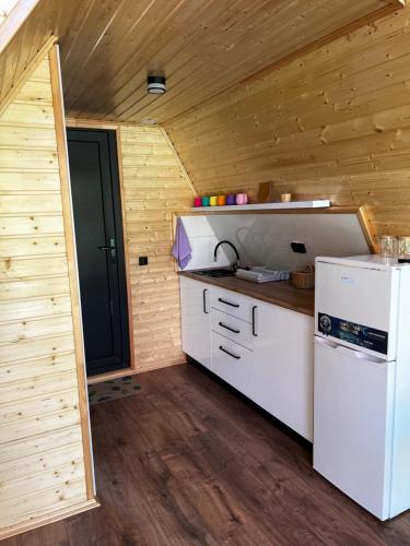 cocina con nevera blanca y pared de madera en Sweet Cottage, en Kobuleti
