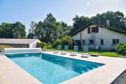 une piscine avec des chaises et une maison dans l'établissement Maison familiale au vert avec piscine et pétanque, à Biaudos