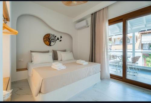 a white bedroom with a bed and a large window at Meltemi Marmaras in Neos Marmaras