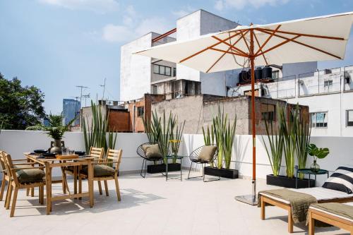 a patio with a table and chairs and an umbrella at AmazINN Collection CDMX Insurgentes in Mexico City