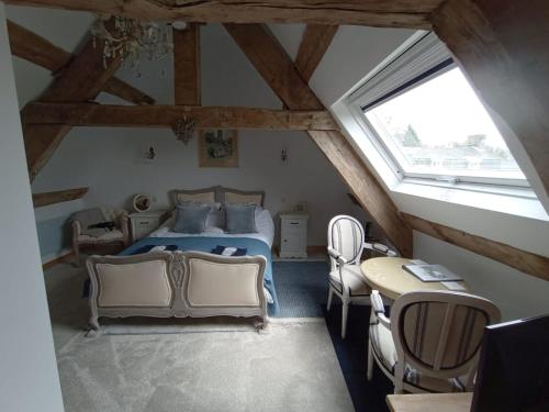 a bedroom with a bed and a table and chairs at Le Presbytere in Beauficel