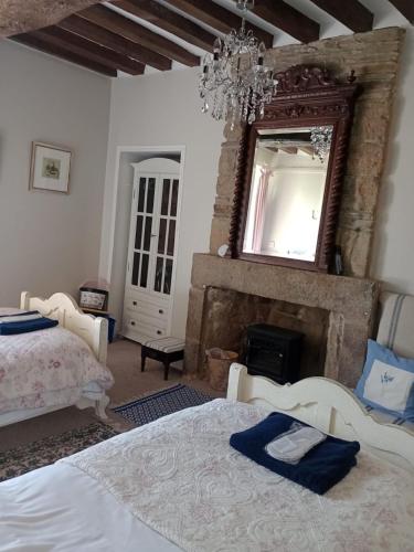 a bedroom with two beds and a mirror and a fireplace at Le Presbytere in Beauficel