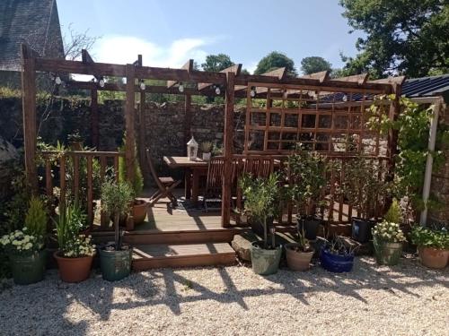 a garden with a wooden pergola and potted plants at Le Presbytere in Beauficel