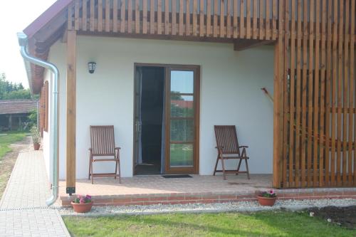 two chairs sitting on a patio in front of a house at Malomkő Apartman in Zsira