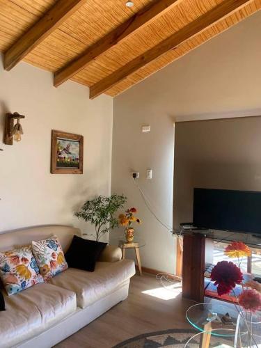 a living room with a couch and a flat screen tv at Chalet con Tinaja LicanRay in Challupen