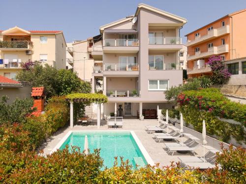 an apartment building with a swimming pool and chairs at Azalea Apartments in Podstrana