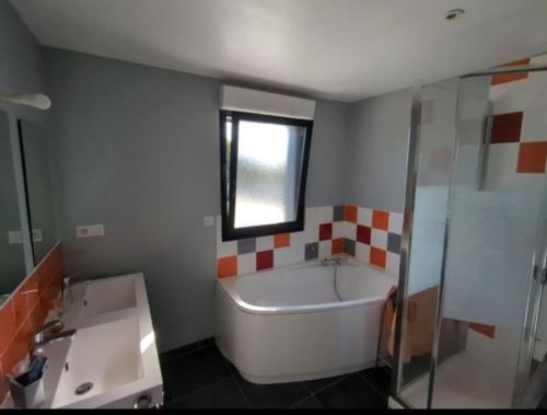 une salle de bain avec une baignoire et un lavabo dans l'établissement Maison de famille, 5min des plages, à Saint-Alban