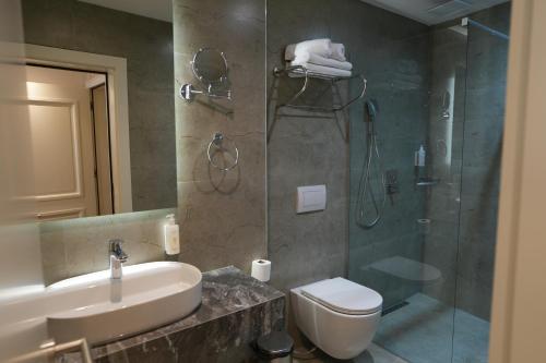 a bathroom with a shower and a sink and a toilet at Avdissons Hotel in Prizren