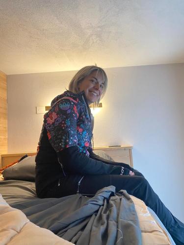 a woman sitting on top of a bed at Inner Holiday Dolomites 5 in Dimaro