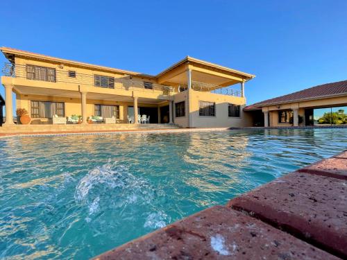 a swimming pool in front of a house at Ambience on N2 Boutique Hotel in Kokstad