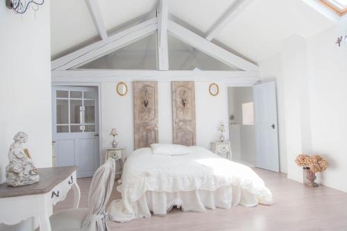 une chambre blanche avec un lit, une table et des chaises dans l'établissement Le Mas d'Elise, à Saint-Hippolyte-de-Caton
