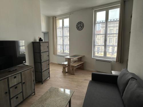 un salon avec un canapé et une télévision à écran plat dans l'établissement Chez Zélie, à Saintes