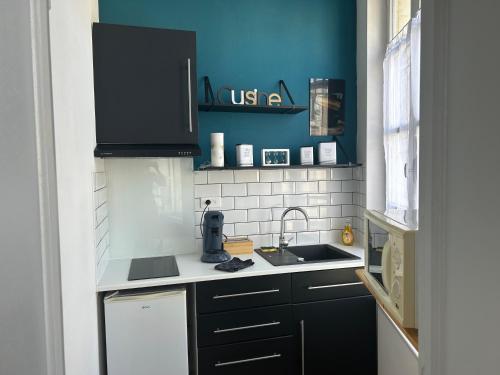 - une cuisine avec des placards noirs et un évier dans l'établissement Chez Zélie, à Saintes