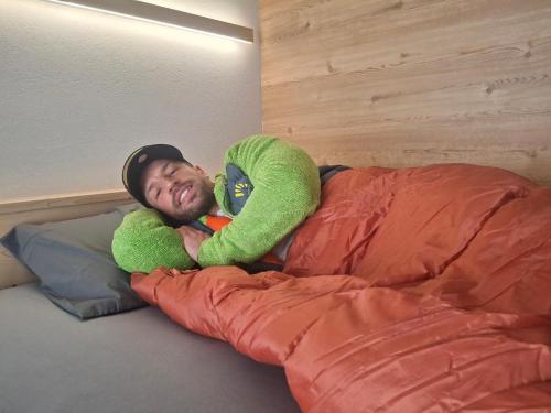 a man is laying on a bed with a stuffed animal at Inner Holiday Dolomites 5 in Dimaro