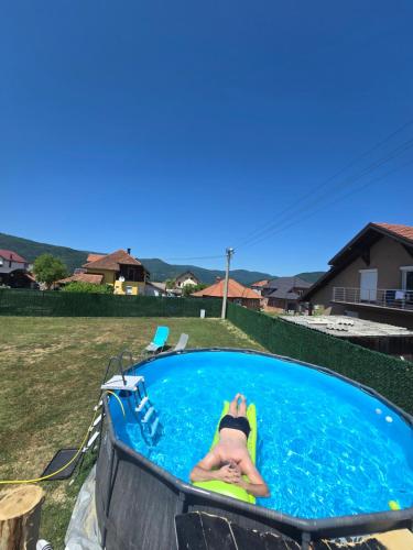 a person laying on a raft in a swimming pool at Apartman Dimitrijevic in Bajina Bašta