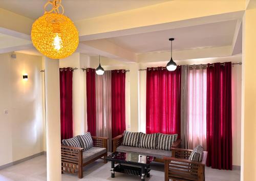 a living room with red curtains and chairs and a table at Tea sprig villa in Boralanda