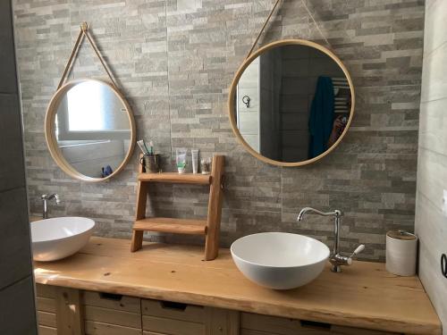 une salle de bain avec deux lavabos et deux miroirs dans l'établissement La maison de Nico et Amandine, à Commequiers