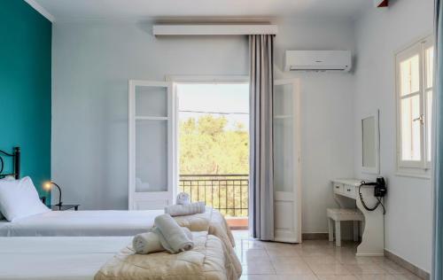 a bedroom with two beds and a balcony at Fexulis Studios & Suites in Agios Nikolaos