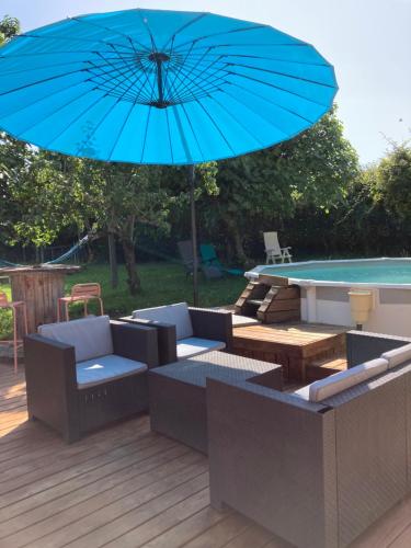 un parasol bleu assis sur une terrasse à côté d'une piscine dans l'établissement Gîte 10 personnes dans la Nature proche Océan Landes, à Heugas