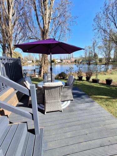 a table and chairs with an umbrella on a deck at Holiday Home on Billing Aquadrome in Great Billing