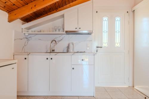 a kitchen with white cabinets and a window at Fexulis Studios & Suites in Agios Nikolaos
