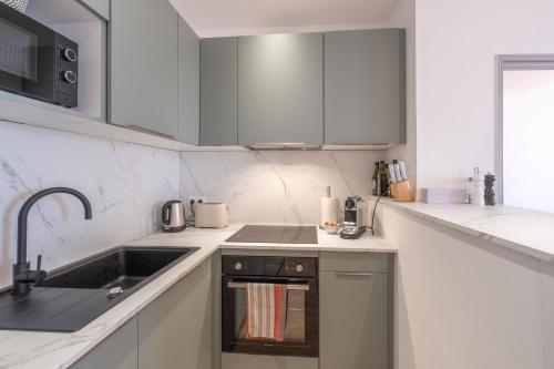 une cuisine blanche avec un évier et une cuisinière dans l'établissement T2 40m2 climatisé centre ville FESCH, à Ajaccio