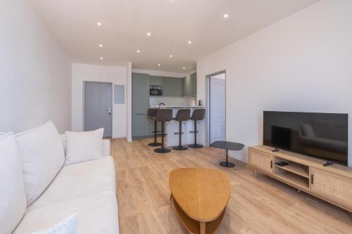 un salon avec un canapé blanc et une télévision dans l'établissement T2 40m2 climatisé centre ville FESCH, à Ajaccio