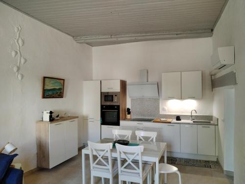 トレイユにあるGites Torreillans - Nid douilletの白いキャビネットとテーブルと椅子のあるキッチン