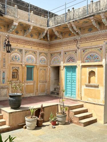 a building with stairs and potted plants in a courtyard at Mandawa Kothi in Mandāwa
