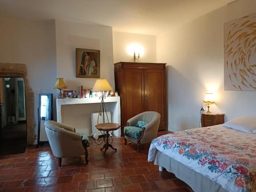 - une chambre avec un lit, des chaises et une cheminée dans l'établissement Les Mimosas, à Lecques