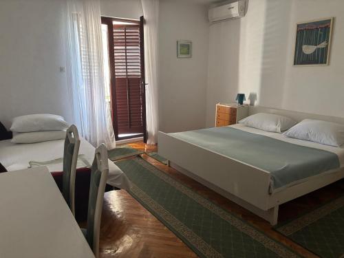 a bedroom with two beds and a door to a window at Apartments Radulović in Biograd na Moru