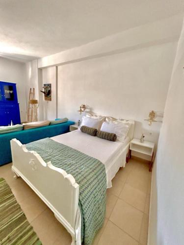 a bedroom with a white bed and a blue couch at Rosalia Studio Megalochori in Megalochori