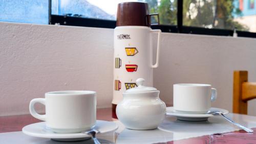 a table with two coffee cups and a juicer at La Estación San Pedro in Cusco