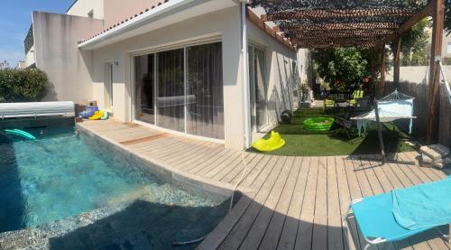 une cour arrière avec une piscine et une terrasse en bois dans l'établissement Villa d'architecte avec piscine privée, idéal pour une famille, à Saint-Aunès