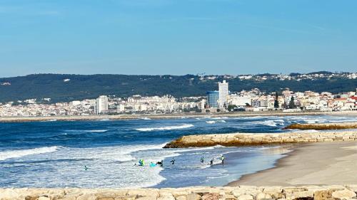a beach with people in the water and a city at Casa Sol e Mar by Férias em Figueira in Figueira da Foz