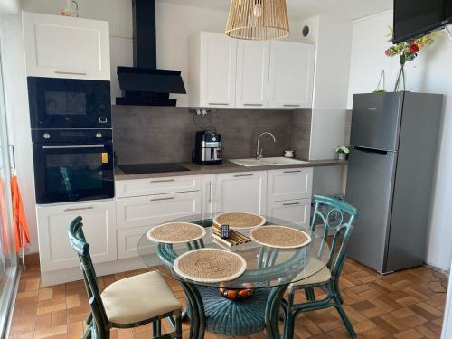 une cuisine avec une table, des chaises et un réfrigérateur dans l'établissement Appartement Vue Mer, au Barcarès