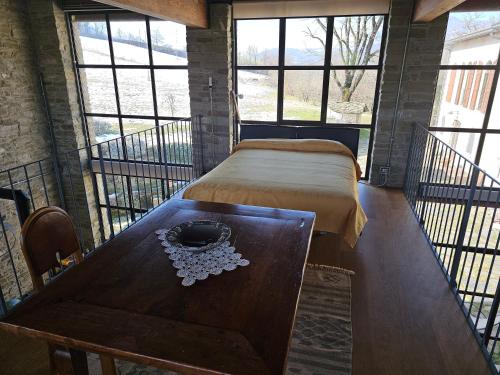 a room with a bed and a table and windows at Sogni nel Bosco in Varsi