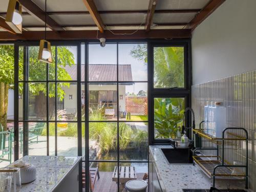 an open kitchen with large windows and a view of a yard at Karuna Villa Prambanan in Yogyakarta
