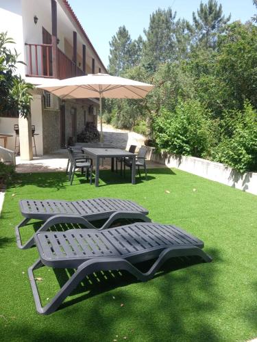 two picnic tables and an umbrella on a lawn at Casa Vale Nicolau in Arganil